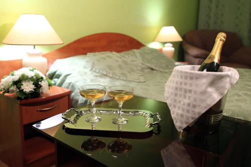 two glasses of wine on a table next to a bed at Hotel Dauria in Chita