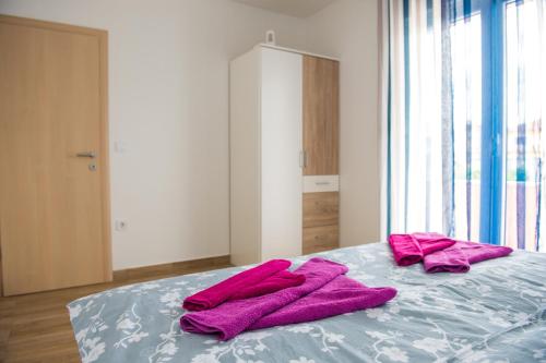 a bed with pink towels on top of it at Apartments Villa Monique in Rogoznica