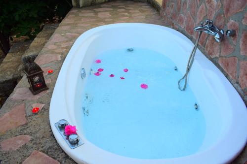 una vasca da bagno riempita di acqua con fiori di Anna's Stone House a Megála Khoráfia