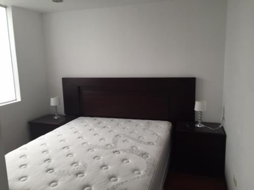 1 dormitorio con 1 cama blanca y 2 mesitas de noche en Departamento Acogedor en los Portales de Cayma, en Arequipa