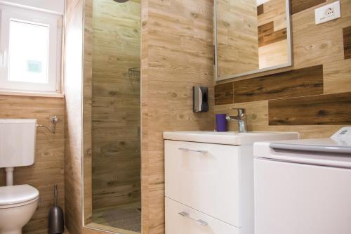 a bathroom with a toilet and a sink and a shower at Apartments Villa Monique in Rogoznica