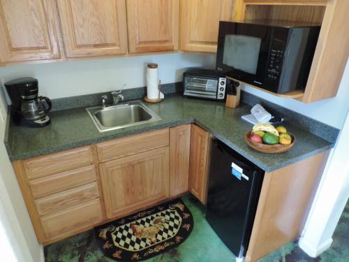 a small kitchen with a sink and a microwave at Hale Pua Villa - Seaside Studio in Koloa