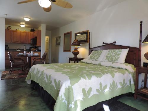 a bedroom with a large bed and a kitchen at Hale Pua Villa - Seaside Studio in Koloa