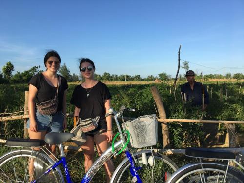 three women standing next to their bikes in a field at Riverside Hamlet Homestay & Villa in Hoi An
