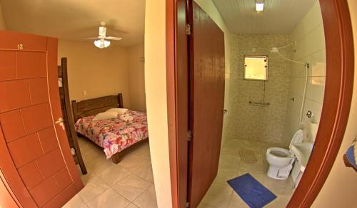 uma casa de banho com um chuveiro, um WC e uma cama em Pousada Natalino Broleze em Águas de Lindoia