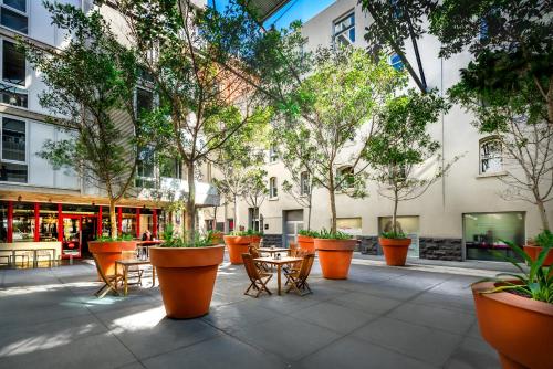a courtyard with tables and chairs and trees at Tribeca Serviced Apartments in Melbourne