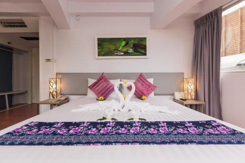 a bedroom with a white bed with purple flowers on it at ON Hotel Phuket - SHA in Karon Beach