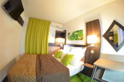 a hotel room with a bed with a green curtain at A&H PRIVILÈGE Lyon Est - Saint Priest Eurexpo in Saint-Priest