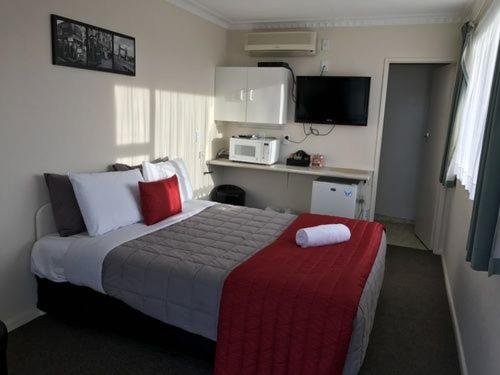 A bed or beds in a room at Ascot Oamaru Motel
