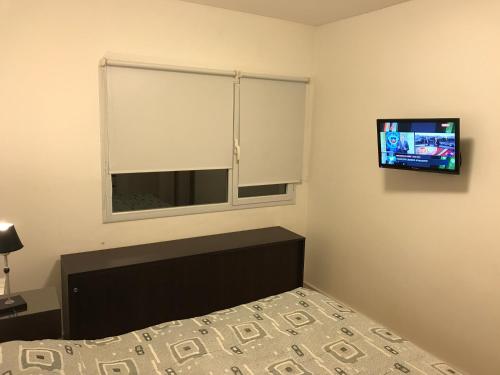 a bedroom with a bed and a tv on the wall at Marco Polo Platinum Apartamento in Mar del Plata