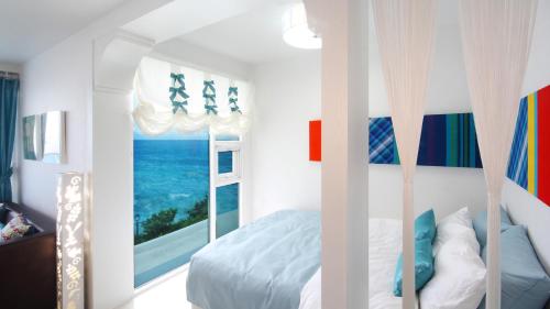 a bedroom with a bed with a view of the ocean at Blue & White Pension in Namhae