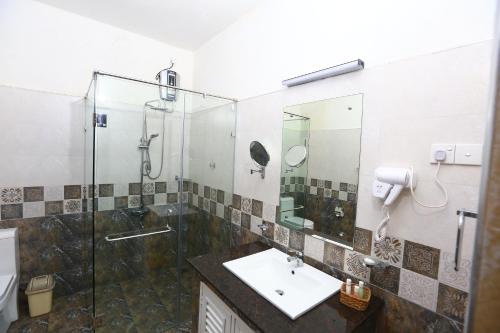 y baño con ducha acristalada y lavamanos. en Peradeniya Rest House, en Kandy