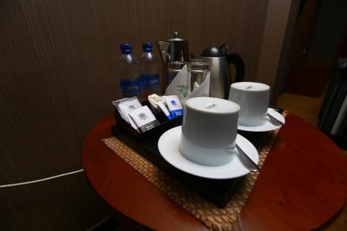 a table with two cups and plates and bottles of water at Peradeniya Rest House in Kandy