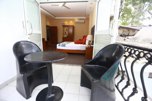 a balcony with two chairs and a table and a bed at Peradeniya Rest House in Kandy