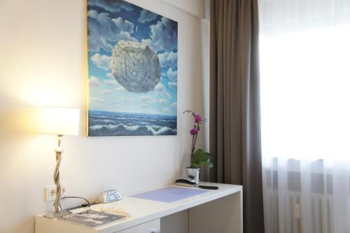 um quarto com uma secretária com um quadro na parede em Business Wieland Hotel em Düsseldorf