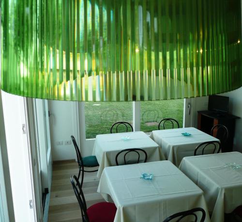 un restaurante con mesas y sillas blancas y una lámpara de araña en Agriturismo Campoverde, en Camponogara