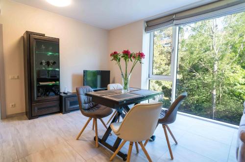 a dining room with a table and chairs and a window at Apartamentai Voveraite in Palanga