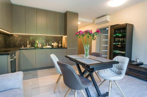 a kitchen with a table and chairs with a vase of flowers at Apartamentai Voveraite in Palanga