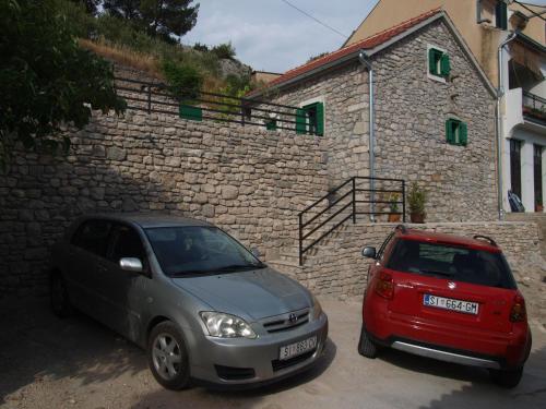 two cars parked in front of a stone building at Holiday Home Anna in Skradin