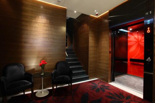 un vestíbulo con 2 sillas y una escalera con alfombra roja en Sohotel, en Hong Kong
