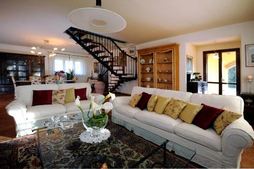 a living room with two white couches and a staircase at Agriturismo - B&B L'Acquacotta in Castiglione della Pescaia