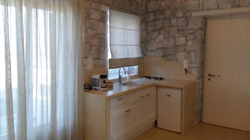 a kitchen with a sink and a stone wall at Milo Milo Suites in Mandrakia