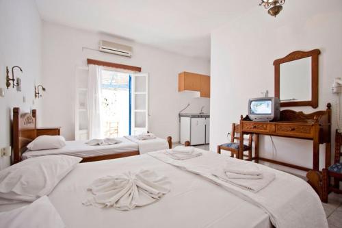 una camera con 4 letti bianchi e una TV di Hotel Landeris a Katápola
