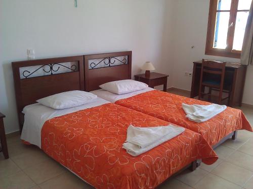 um quarto com 2 camas com lençóis vermelhos e almofadas brancas em Agnanti Apartments em Vathi