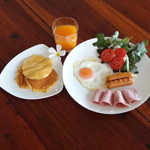 deux assiettes de petit-déjeuner avec des œufs et du jambon et un verre de jus d'orange dans l'établissement Fisherman Koh Tao, à Koh Tao