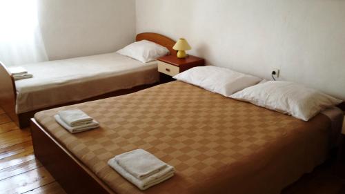 Duas camas num pequeno quarto com uma mesa e um candeeiro em Apartments Princip em Orlec