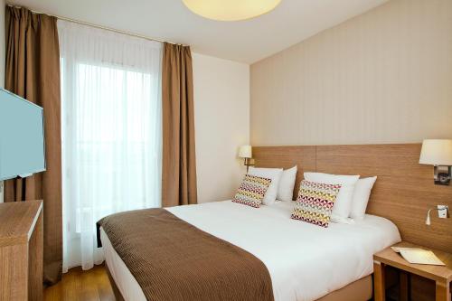 a hotel room with a bed and a television at Residhome Bois Colombes Monceau in Bois-Colombes