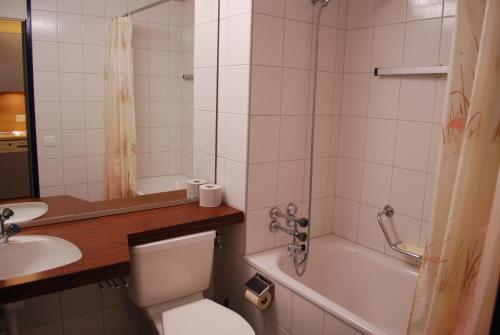 a bathroom with a toilet and a tub and a sink at Apart Holidays - Haus Acletta in Disentis