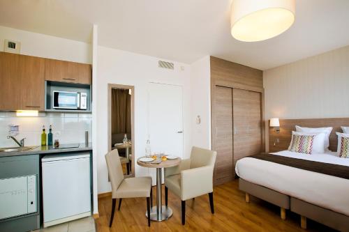 a hotel room with a bed and a table and a kitchen at Residhome Bois Colombes Monceau in Bois-Colombes