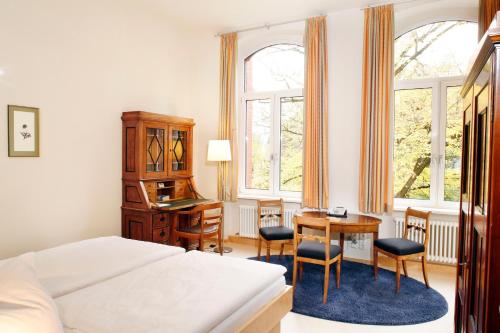 Schlafzimmer mit einem Bett, einem Schreibtisch und einem Tisch in der Unterkunft Gäste- und Tagungshaus am Glockengarten in Berlin