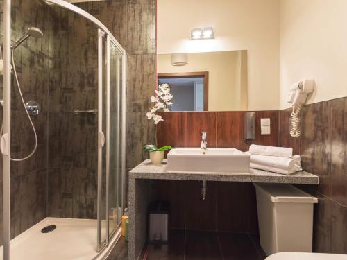 uma casa de banho com um lavatório e um chuveiro em VacationClub - Sand Hotel Apartment 201 em Kolobrzeg