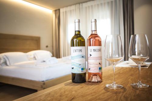 two bottles of wine and two glasses on a table at Agriturismo La Pertica in Costermano sul Garda