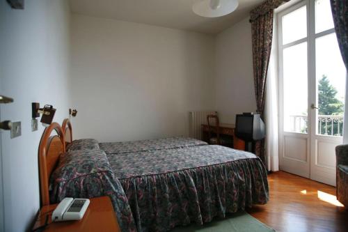 a bedroom with a bed and a table and a window at Hotel Villa Rosy in Premeno