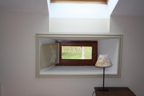 ein kleines Fenster in einer weißen Wand mit einer Lampe in der Unterkunft La Maison d'Anais in Vic-en-Bigorre