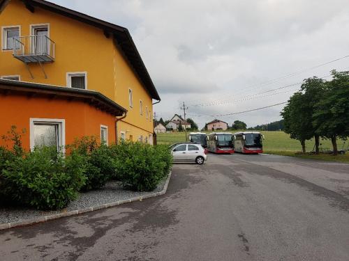a car parked in front of a house with two buses at Hotel Kreuzwirt in Engerwitzdorf