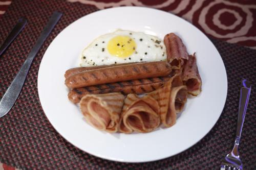 a plate of breakfast food with eggs sausage and waffles at Hotel Cama in Chandīgarh