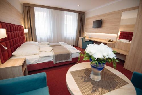 a hotel room with a bed and a vase of flowers at Hotel Texicana in Sulechów