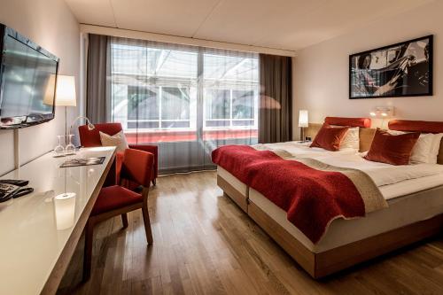 ein Hotelzimmer mit einem Bett, einem Schreibtisch und einem TV in der Unterkunft First Hotel G in Göteborg