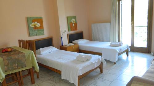 a hotel room with two beds and a table at Forkis Apartments in Vathi, Ithaka
