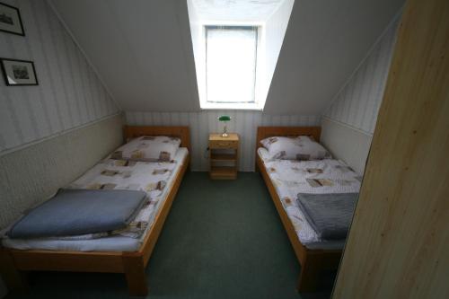 two beds in a small room with a window at Gyula-tanya Vendégház in Csongrád