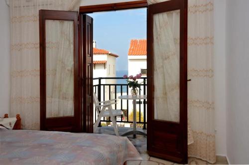 1 dormitorio con puerta abierta a un balcón en La Plage, en Kokkari