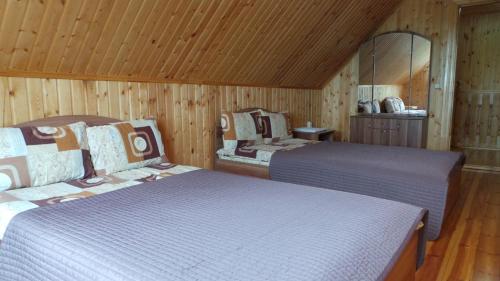 two beds in a room with wooden walls at Hunter Village in Uglich