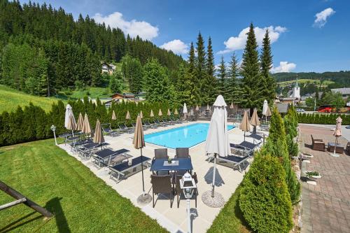 a swimming pool with umbrellas and chairs and a pool at Hotel Happy Filzmoos in Filzmoos