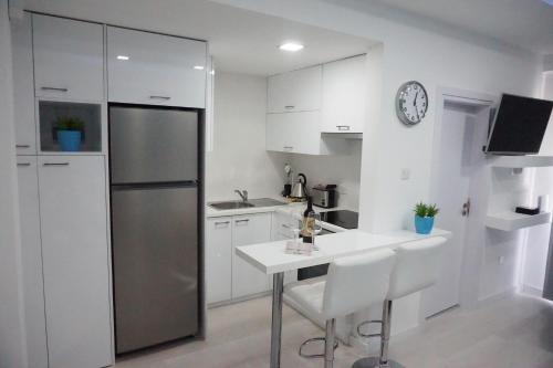 Lazuli Beach Apartment 209 في لارنكا: مطبخ مع ثلاجة وطاولة وكراسي
