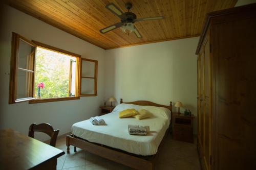 a bedroom with a bed with a ceiling fan and a window at Nereidi Villas in Porto Ozias