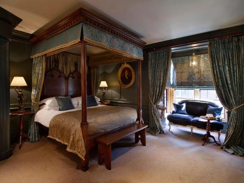a bedroom with a canopy bed and a blue chair at Hazlitt's in London
